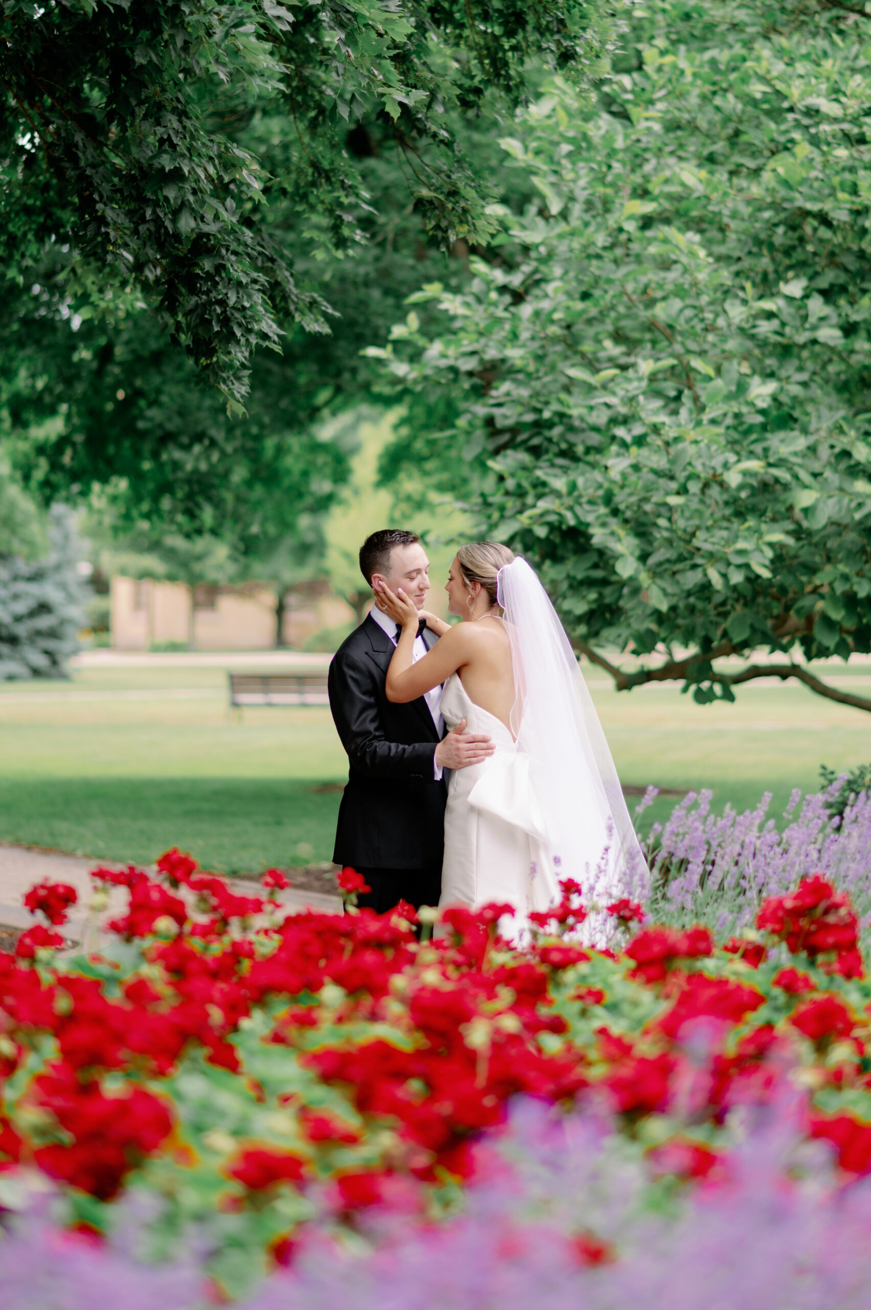 Bride and Groom in God Quad at The University of Notre Dame, embracing with red flowers in the foreground