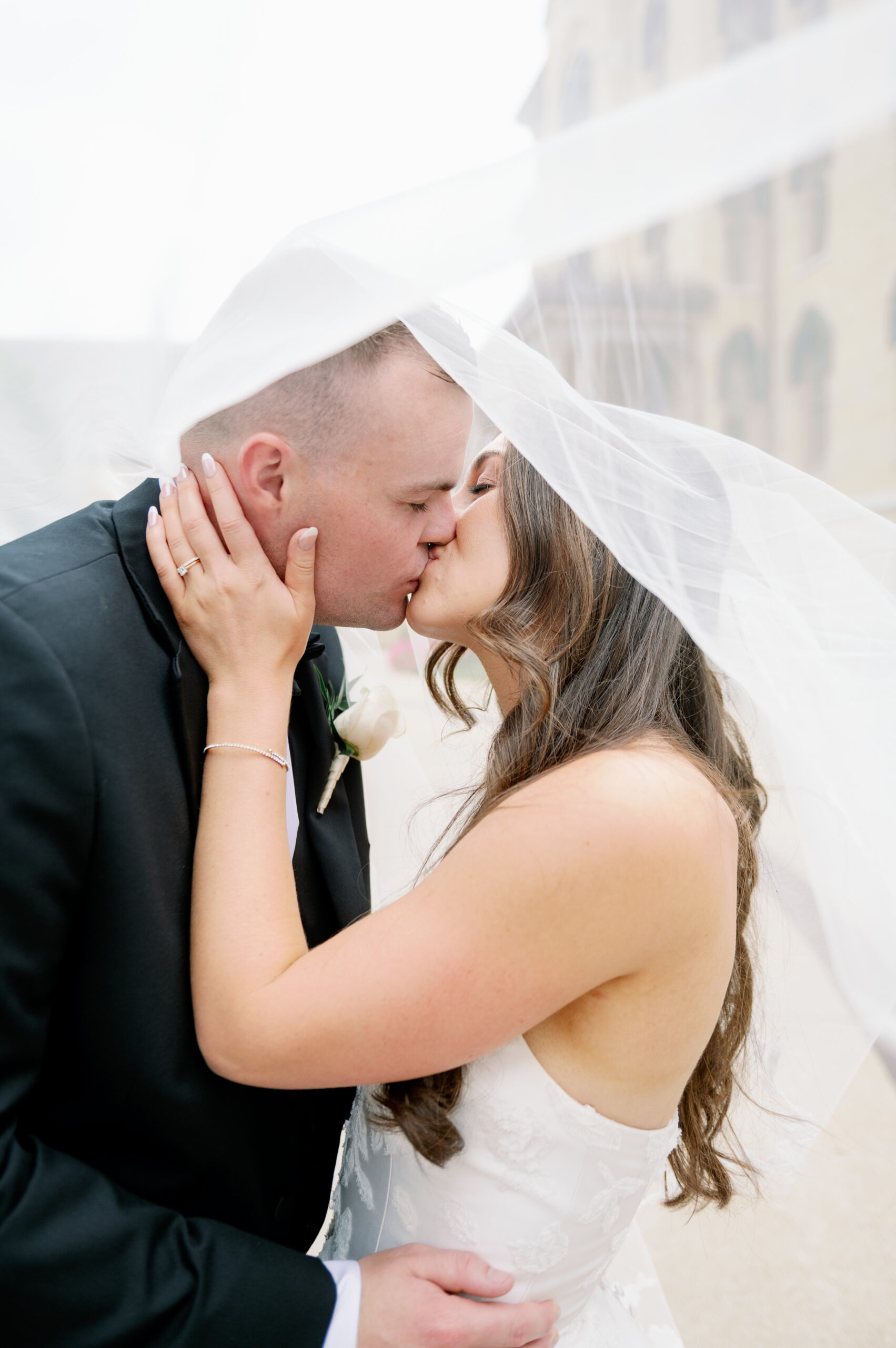 A bride and groom kiss under her veil on their wedding day at Notre Dame stadium.