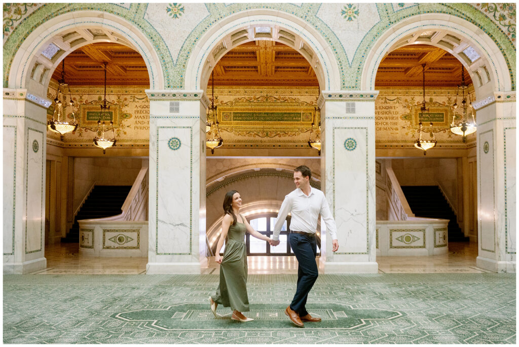 Chicago Cultural Center engagement session with couple walking hand in hand through ornate marble halls