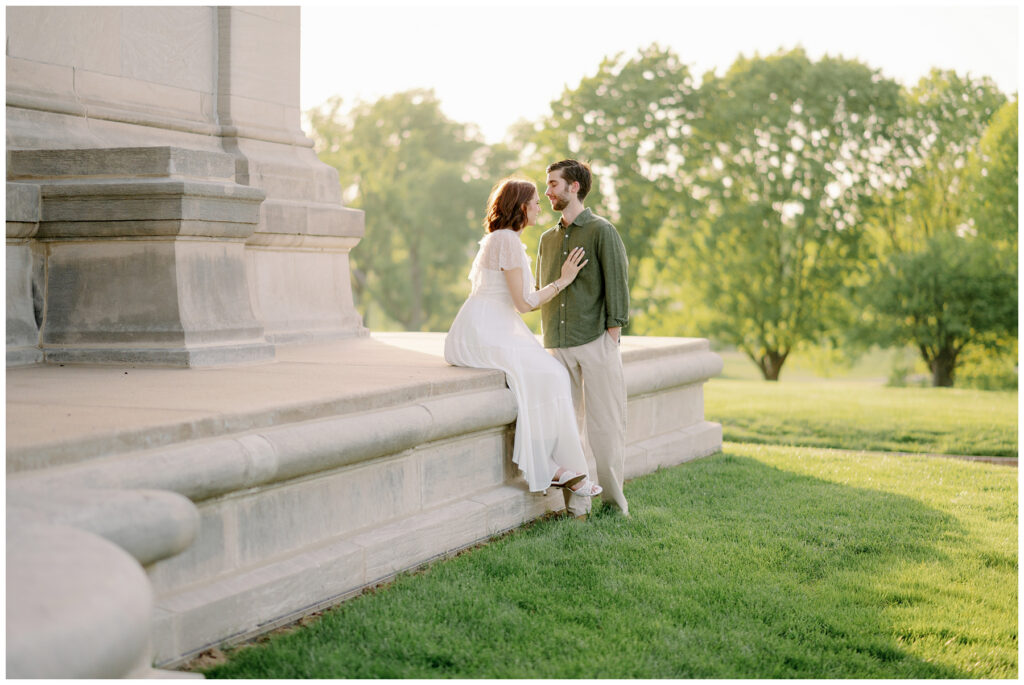 Couple sitting together on a stone ledge near the St. Louis Art Museum, surrounded by soft evening light and greenery