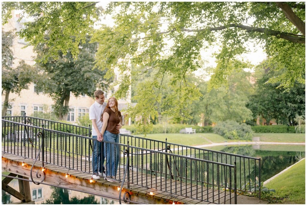Couple embracing on the iconic bridge over the pond during summer Saint Mary's College engagement photos.