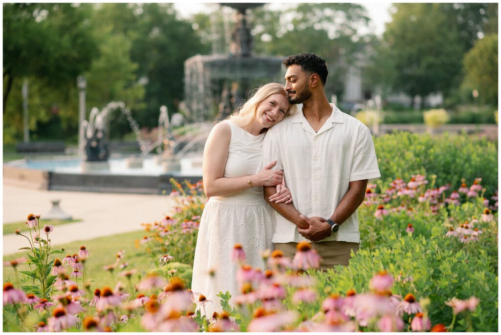 Couple embracing in the Leeper Park flower gardens during golden hour engagement photos in South Bend, Indiana.