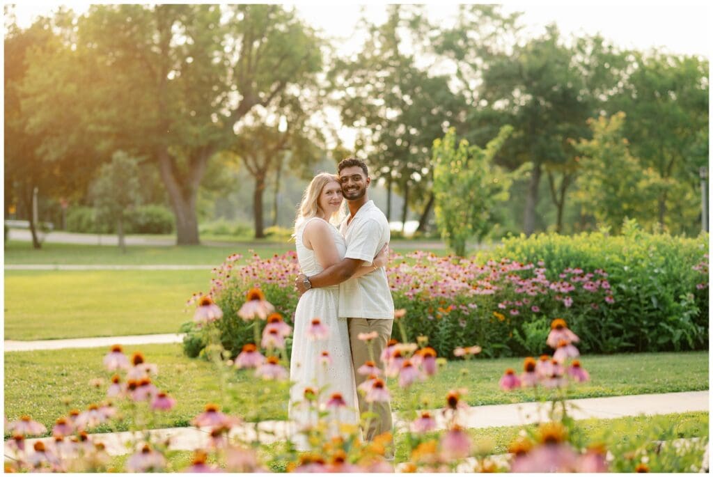 Couple hugging in the flower gardens at Leeper Park during a summer engagement session.